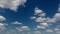 Movement of white clouds against a blue sky.