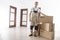 Mover with cardboard boxes in new apartment. Relocation services worker in indoor house. Loader in uniform with box