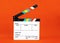 A movie clapper on orange background film, cinema and video photography concept