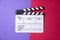 Movie clapper on purple and red background; film, cinema and video photography concept