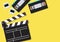 Movie clapper and video cassette tapes on yellow background