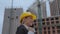 Moving camera. A woman excitedly and joyfully talking on the phone against the backdrop of a construction site. Woman in