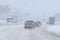 Moving car on snowy winter road among frozen forest after sleet. Cold weather, snowstorm, bad visibility, slippery road