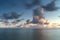 Moving clouds above large lake with smooth water and a sunset view from the coast