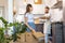 Moving day, couple standing together in kitchen, unpacking carton package