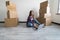 Moving house concept. Young woman relaxing on floor searching on computer in new home.