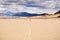 Moving rocks and their tracks at the Racetrack Playa; mountains and clouds scenery in the background; Death Valley National Park,