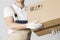 Moving service worker holds cardboard box close-up. Mover in uniform holding parcel in hands. Relocation services man