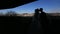 Moving view toward the silhouette of newlyweds tenderly kissing on the balcony with cityscape.