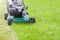 Mowing or cutting the long grass with a green lawn mower