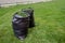 Mowing a household garden lawn with black bag of grass clippings