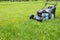 Mowing lawns. Lawn mower on green grass. mower grass equipment. mowing gardener care work tool close up view sunny day