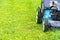 Mowing lawns, Lawn mower on green grass, mower grass equipment, mowing gardener care work tool, close up view, sunny day.