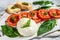 Mozzarella burrata salad with basil leaves and tomatoes. Gray background. Top view