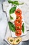 Mozzarella burrata salad with basil leaves and tomatoes. Gray background. Top view