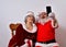 Mr and Mrs Santa Claus having fun using a smart pone