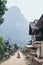 Muang Ngoi, Laos - May 2019: Laotian woman with two buckets walking on the central street of the village