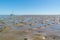 Mud flat with casts of lugworm and dried out sailboat at low tide on Waddensea, Netherlands