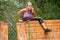 Mud race participant climbing over an obstacle