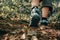 Muddy boots of hiker on forest trail. Traveler feet on ground with fallen leaves. Close up of the sole of dirty shoes. Hiking