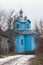 Muddy dirt road lead to Assumption of Mary russian Orthodox church, wooden temple with blue walls