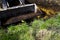 Muddy excavator bucket going to dig soil in grassy field in countryside