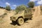 Muddy off-road car after it was pulled out of the mud on an adventurous off-road trip with steep slope in the background