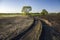 Muddy road through the field and tractor tracks