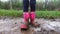 Muddy rubber boots in dirty rain. Child play in puddle