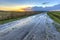 Muddy wet sand lane in grassland landscape