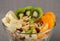 Muesli with banana kiwi nuts oranges in a glass bowl