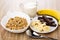 Muesli in bowl, spoon, chocolate and banana in saucer, jug of mi
