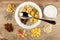 Muesli dried fruits, corn flakes, oatmeal, sunflower seeds, banana chips, spoon in bowl, heaps of ingredients, jug of yogurt on