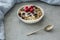 Muesli, raspberries and raisins in a bowl next to a spoon on a