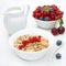 Muesli with red currant, bowl of fresh berries and jug of milk