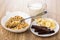 Muesli, spoon in bowl, chocolate and banana in saucer, jug of mi