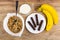 Muesli, spoon in bowl, jug of milk, bananas, pieces of chocolate