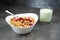 Muesli with srawberry and cranberry with glass of yogurt in white bowl on grey background.