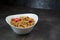 Muesli with srawberry and cranberry in white bowl on grey background.