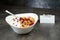 Muesli with srawberry and cranberry with yogurt in white bowl on grey background. Name card with butterflys.
