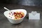 Muesli with srawberry and cranberry with yogurt in white bowl on grey background. Name card with heart.