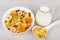 Muesli in white bowl, jug milk and spoon corn flakes