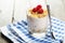 Muesli with yogurt and raspberries in a glass on a brown wooden background.