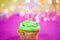 Muffin with green buttercream, pink background, candle