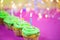Muffin with green buttercream, pink background, candle