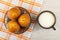 Muffins in paper mold in saucer on napkin, transparent cup with milk on wooden table. Top view