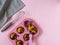 Muffins in a pink cupcake shape, a kitchen spatula with a pink handle, a gray striped towel on a pink background.