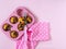 Muffins in pink cupcake shape, kitchen spatula with pink handle, pink towel with white polka dots on pink background.