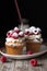 Muffins with soft cream and fresh raspberry powdered with sugar on a plate, bottle of milk with straw, rustic background