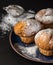 Muffins sprinkled by powdered sugar on blue plate with strainer behind.